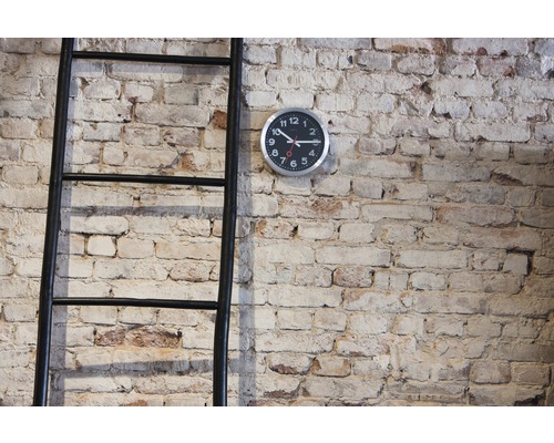 Dekoratívny rebrík a nástenné hodiny pred tehlovou stenou