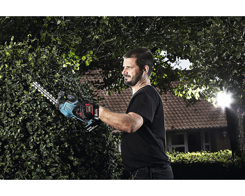 Muž strihá živý plot pomocou akumulátorových nožníc na živý plot