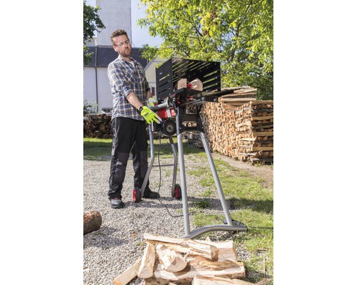 Muž obsluhuje pílku na palivové drevo na rezanie dreva vonku.