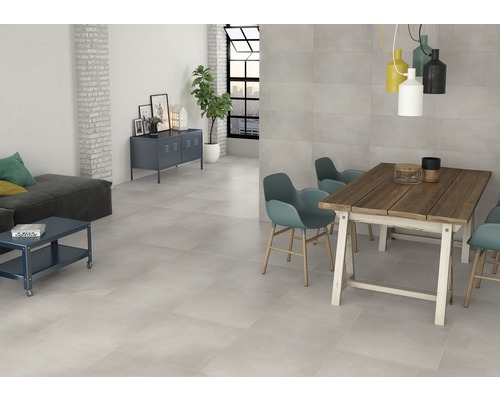 Svetlá izba so sivou dlažbou, jedálenským stolom, stoličkami a pohovkou.