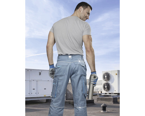 Muž v pracovnom odeve s viacúčelovými nohavicami a rukavicami na streche