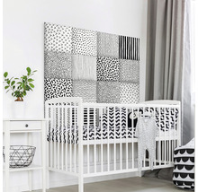 Detská izba s bielou detskou postieľkou a nástennými panelmi s rôznymi vzormi.