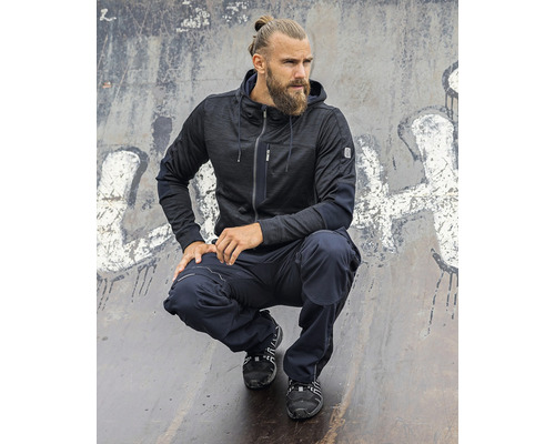 Muž v pracovnom odeve s bundou s kapucňou a pracovnými nohavicami