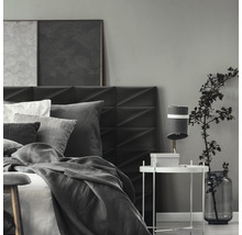 Spálňa s posteľou, nočným stolíkom a dekoráciou v sivých tónoch.