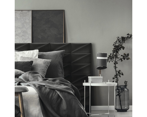 Spálňa s posteľou, nočným stolíkom a dekoráciou v sivých tónoch.