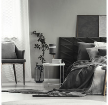 Spálňa s posteľou, nočným stolíkom, lampou a stoličkou.