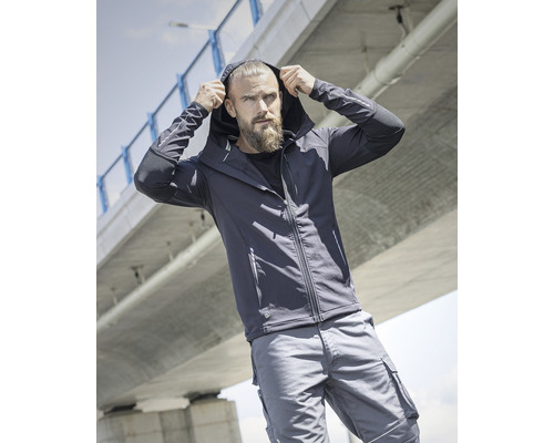 Muž v bunde s kapucňou a pracovných šortkách pod mostom