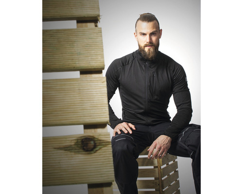 Muž v pracovnom odeve sedí na drevenej palete