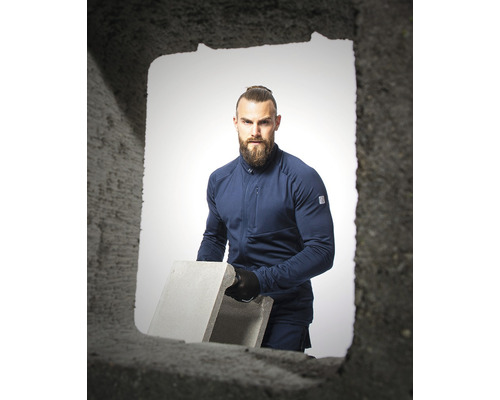 Muž v pracovnom odeve nesie betónový blok.