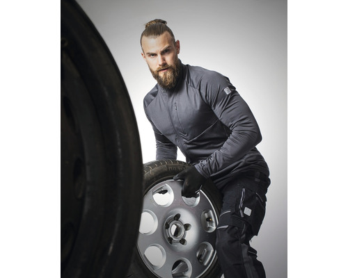 Muž v pracovnom odeve manipuluje s kolesom automobilu