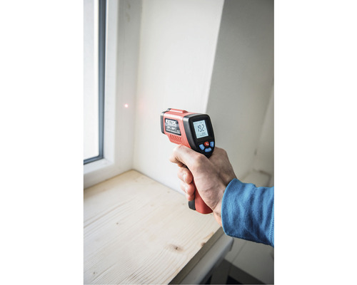 Ruka s infračerveným teplomerom na meranie teploty pri okne