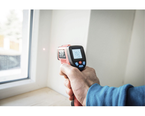 Ruka drží infračervený teplomer na meranie teploty okna