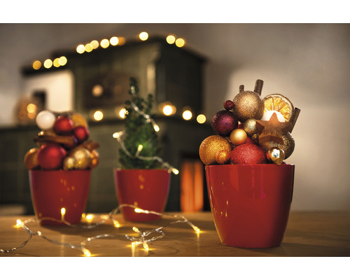 Dekoratívna vianočná scéna s červenými kvetináčmi, vianočnými guľami, hviezdami a svetlami