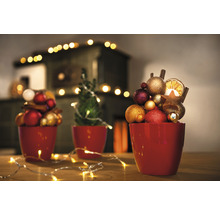 Dekoratívna vianočná scéna s guľami, hviezdami a svetelnou reťazou v červených kvetináčoch