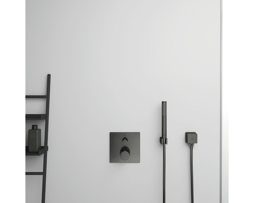 Nástenná sprchová batéria s ručnou sprchou a policou v kúpeľni.