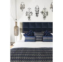 Spálňa s modrým čelom postele, ozdobnými vankúšmi, prikrývkou a lapačmi snov