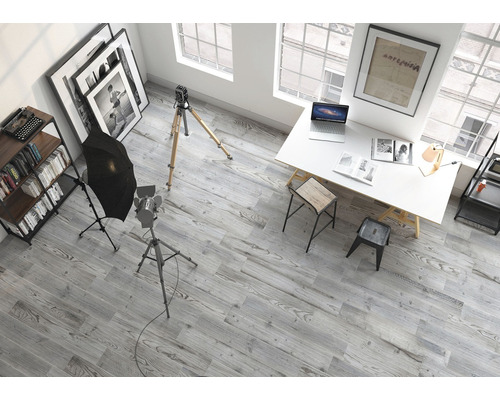 Interiérový pohľad na štúdio s fotografickým vybavením, písacím stolom, policami a sivou drevenou podlahou