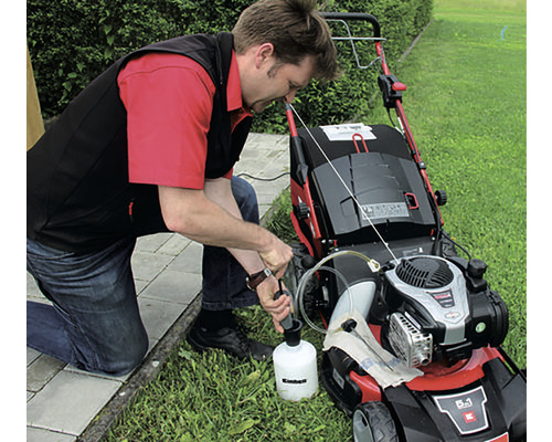 Muž dopĺňa olej do kosačky na trávu