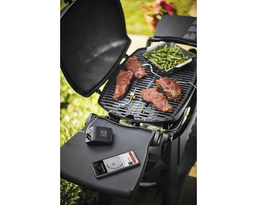 Grilovacia scéna so steakmi, zelenou zeleninou, grilovacím teplomerom a smartfónom na grile