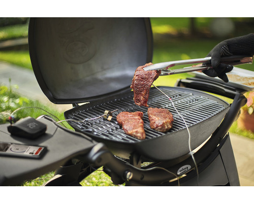 Grilovacia scéna so steakmi na grile a grilovacími kliešťami so steakom