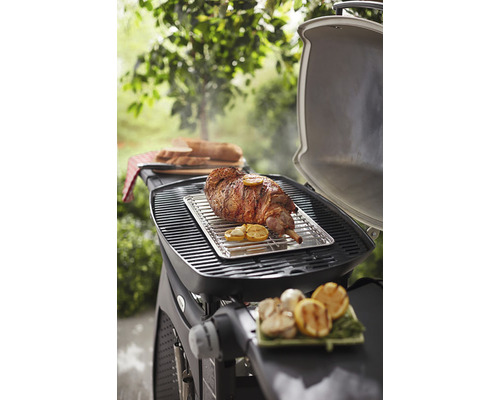 Grilovacia scéna s jahňacím stehnom, citrónom a chlebom na grile vonku.