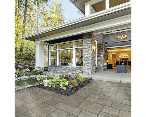 Terasa s dlažobnými kockami pred domom s kamennou fasádou a jazierkom