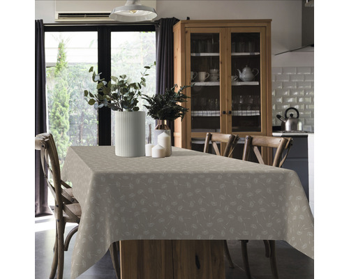 Jedálenský stôl so vzorovaným obrusom, kvetinové vázy a stoličky vo svetlej miestnosti.