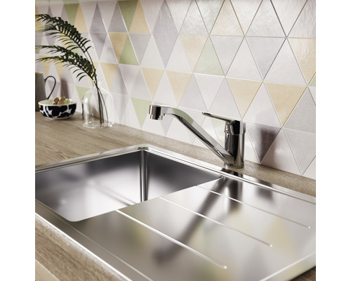 Nerezový drez s odkvapkávacou plochou a batériou pred trojuholníkovými obkladačkami