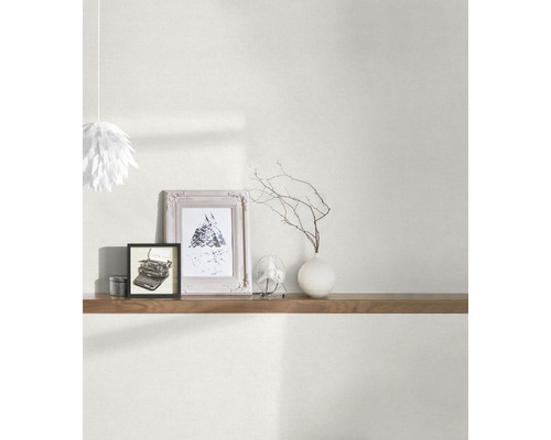 Obývacia izba s tapetou, policou a dekoratívnymi prvkami, ako sú rámy a váza