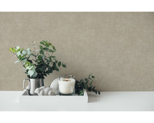 Dekoratívne zátišie scéna s eukalyptovými vetvami, sviečkou a dekoratívnymi prvkami pred štruktúrovanou stenou