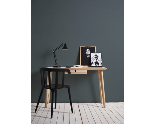 Písací stôl so stolnou lampou, stoličkou a dekoráciou na svetlej drevenej podlahe