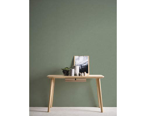 Drevený stôl s dekoráciou pred zelenou stenou