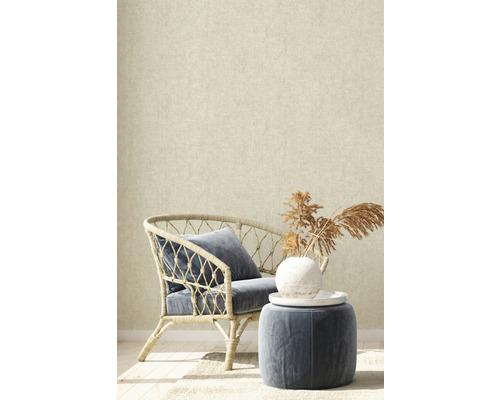 Dekoratívny interiér s ratanovým kreslom, vankúšom a odkladacím stolíkom pred béžovou tapetou.