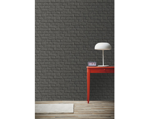 Izba so sivou tehlovou stenou, červeným stolom a lampou.