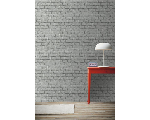 Scéna s tehlovou stenou, stolnou lampou, stolom a kobercom