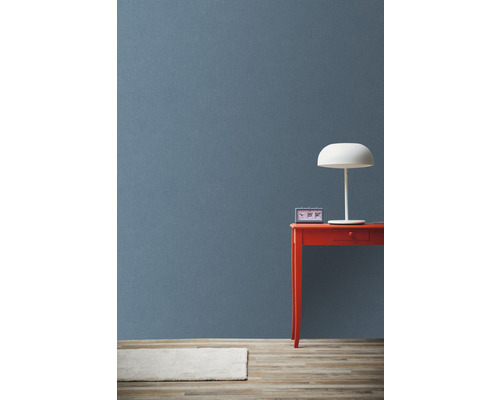 Svetlý koberec, modré pozadie, červený stôl s hodinami a lampou