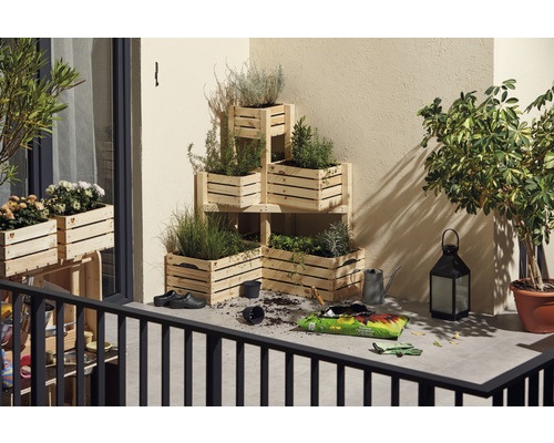 Balkónová scéna s osadenými regálmi z drevených debničiek, kvetinovou zeminou, kanvou a lampášom