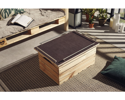 Drevená debna ako konferenčný stolík s doskou a kovovými rúčkami v obývacej izbe.