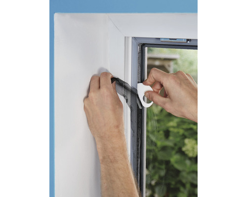 Osoba pripevňuje sieť proti hmyzu k rámu okna pomocou montážneho nástroja.