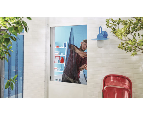 Muž montuje sieť proti hmyzu na okno pre ochranu proti hmyzu.