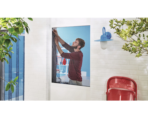 Muž upevňuje sieť proti hmyzu na okno.