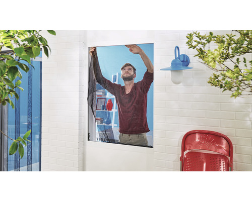 Muž montuje moskytiéru na okno, aby zabránil vniknutiu hmyzu.