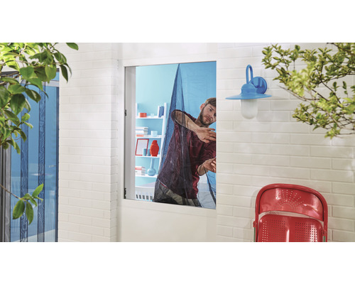 Muž montuje do okna sieť proti hmyzu.