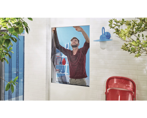 Muž upevňuje sieť proti hmyzu na okno