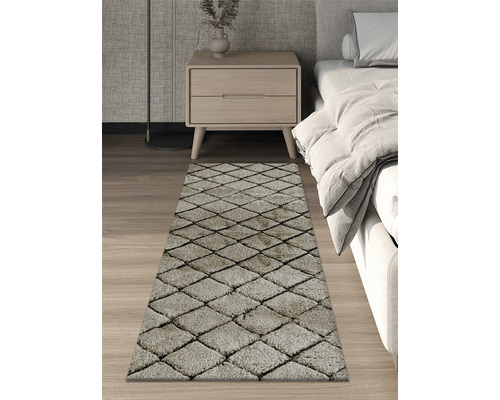 Koberec s kosoštvorcovým vzorom v spálni vedľa postele a nočného stolíka