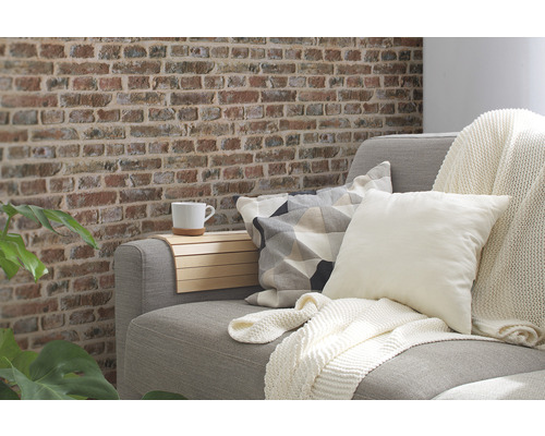 Obývacia izba s pohovkou, vankúšmi, dekou a stenou s tehlovým vzhľadom