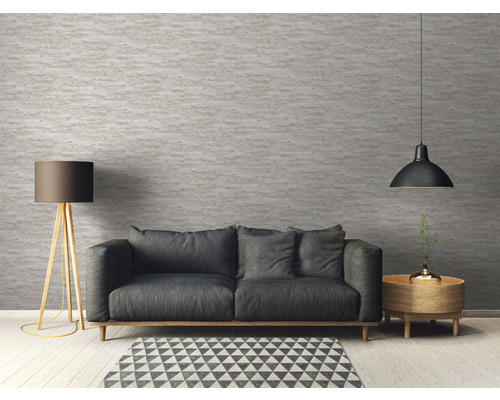 Obývacia izba s pohovkou, stojacou lampou a závesným svietidlom pred štruktúrovanou stenou