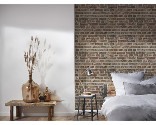 Spálňa s posteľou pred tehlovou stenou a dekoráciou na drevenom stole