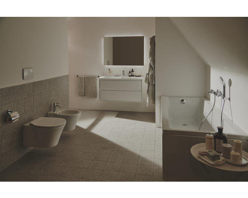 Svetlá kúpeľňa s toaletou, bidetom, umývadlom, osvetleným zrkadlom a vaňou.