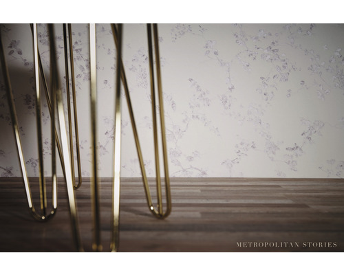 Detailný záber kovových nôh stola pred tapetou so vzorom kvetov.